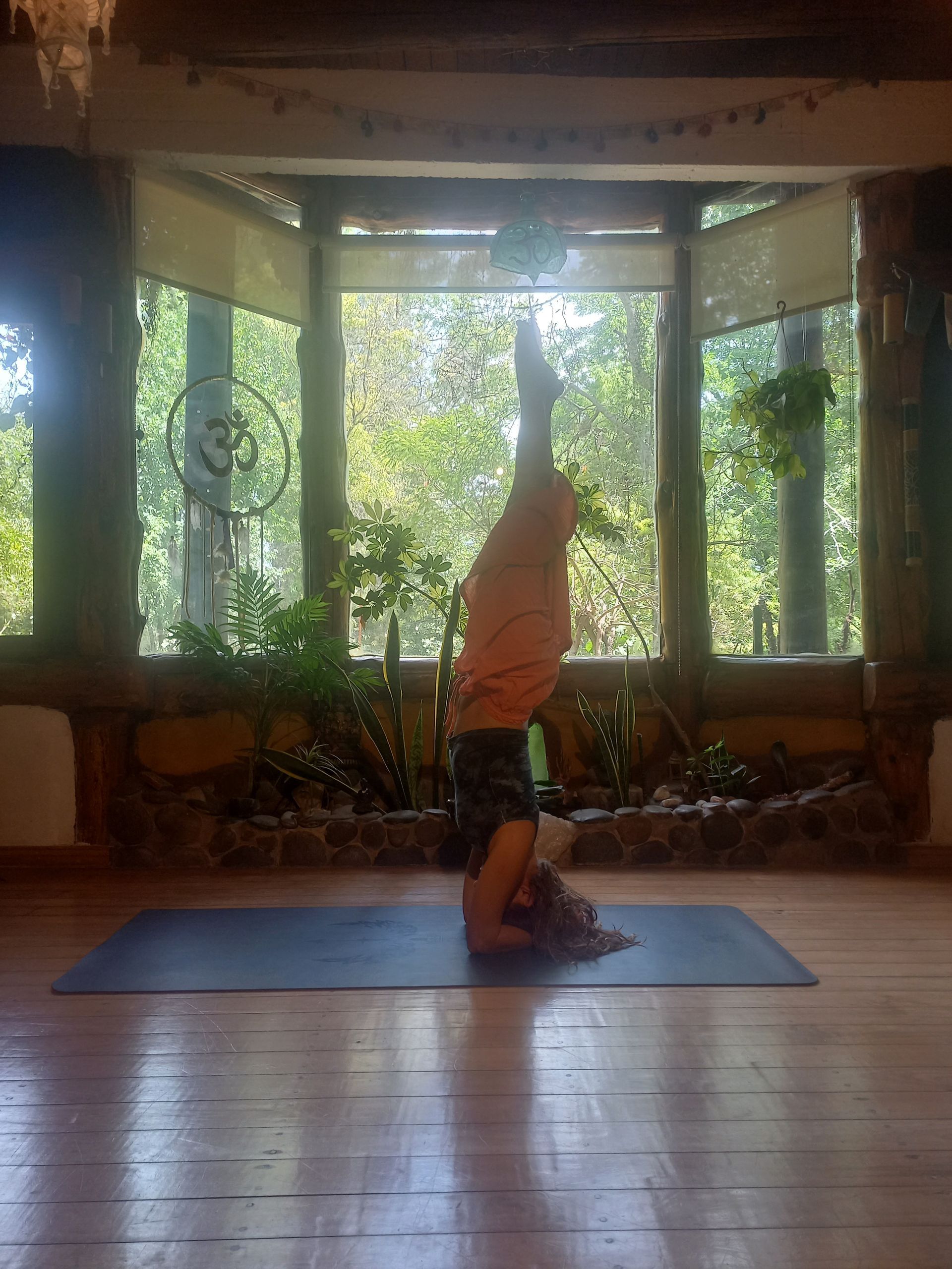 Persona en pose de parada de manos sobre una colchoneta de yoga azul, 