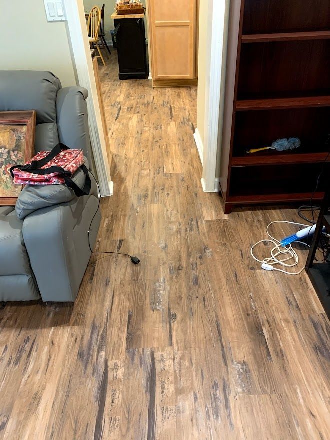 A view of a home interior featuring wood-look laminate flooring leading from a living room toward a kitchen area.