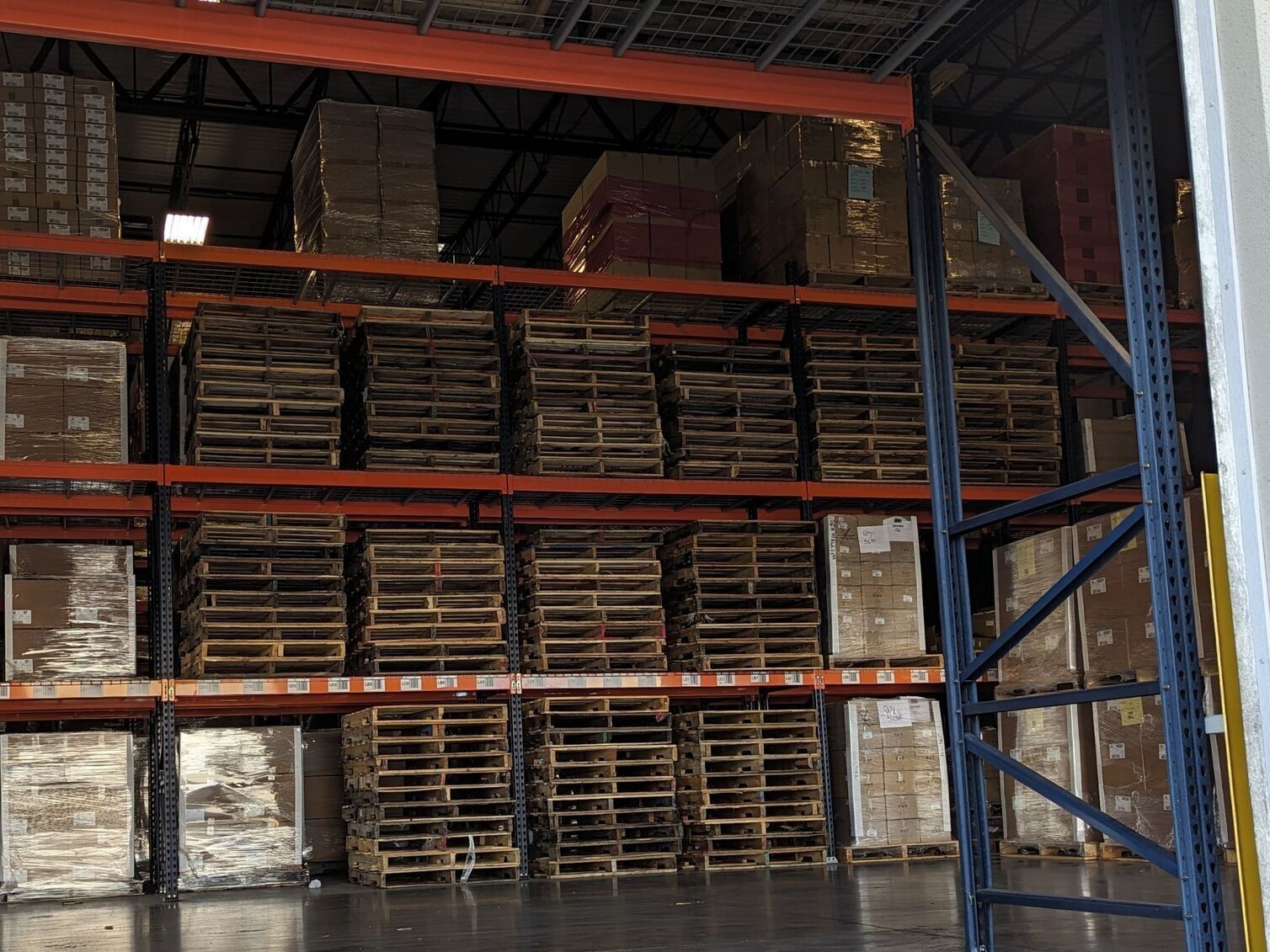 Warehouse shelves stacked with wooden pallets and boxes in a storage area