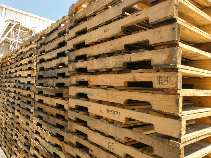 Stacked wooden pallets piled high in a large outdoor storage yard