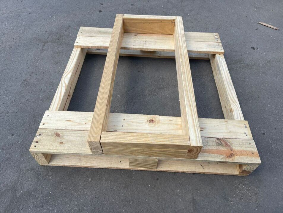 Stacked wooden pallets or crate frames on a gray floor