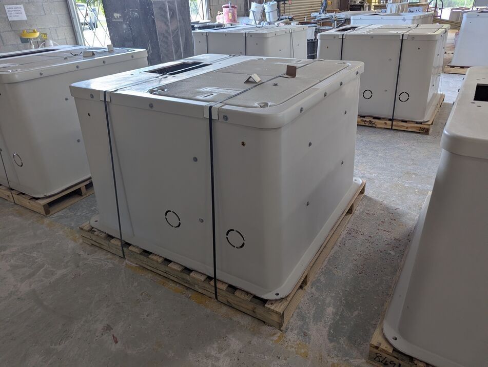 White industrial machines on wooden pallets in a warehouse, with one unit in the foreground.