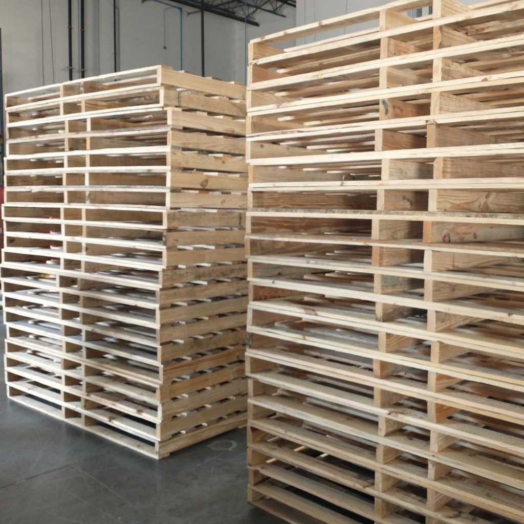 Stacks of wooden pallets in a warehouse with a concrete floor and high ceiling