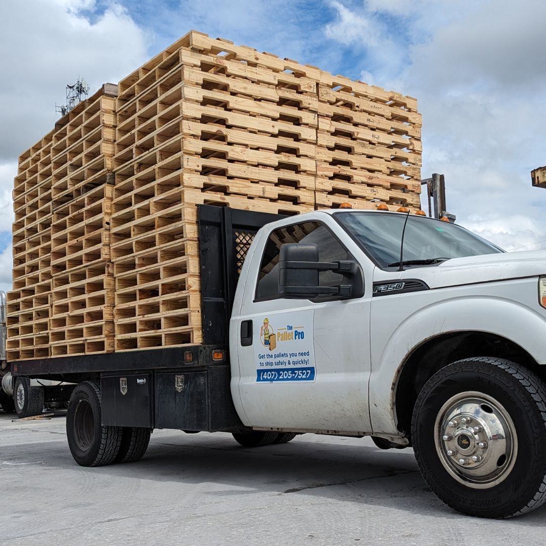 White work truck loaded with stacked wooden pallets in a parking lot