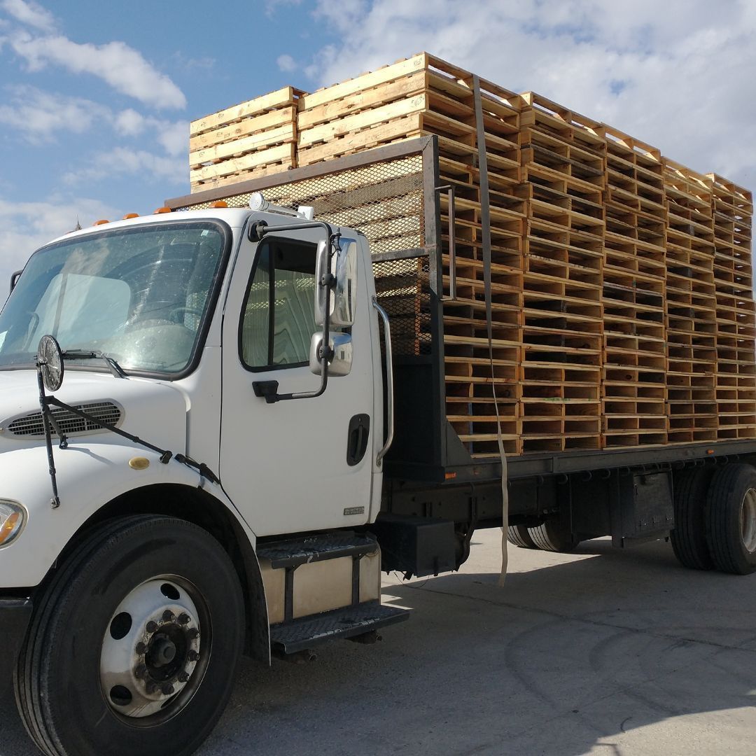 A white truck is loaded with wooden pallets