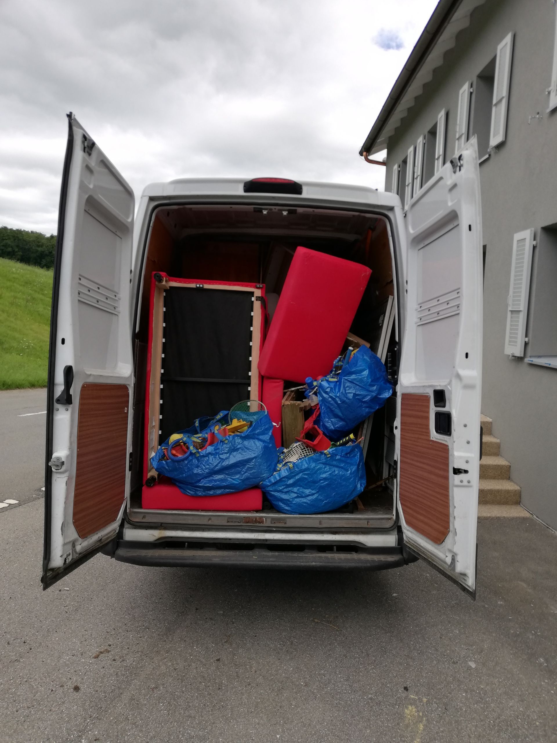 camionnette de déménagement blanche est remplie de meubles et sacs 