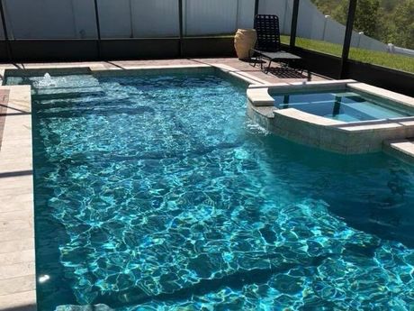 A large swimming pool with a hot tub in the backyard