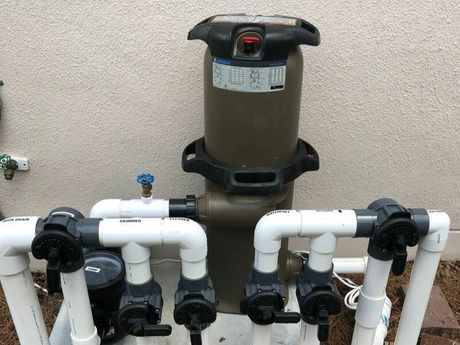 A swimming pool filter is sitting on top of a pile of pipes.