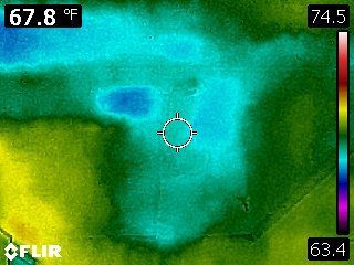 Thermal image showing a surface with varying temperatures from green (cool) to red (warm). 