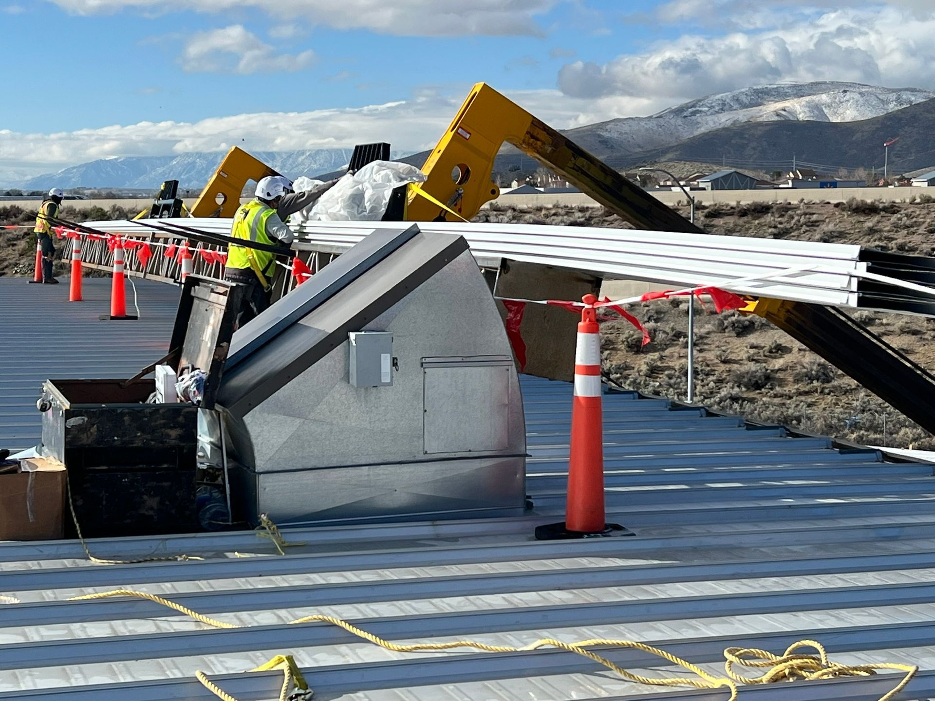Construction worker near a partially constructed solar panel array, with mountains in the background.