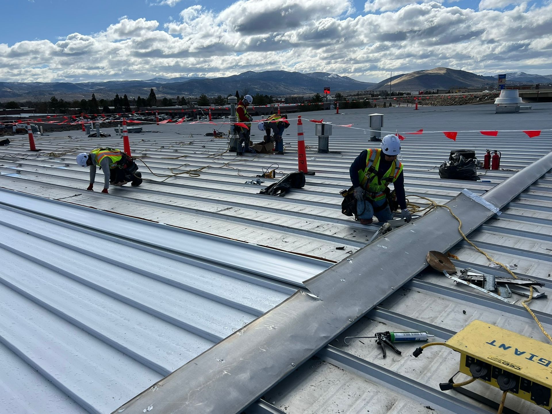Construction workers installing metal roofing on a sunny day.