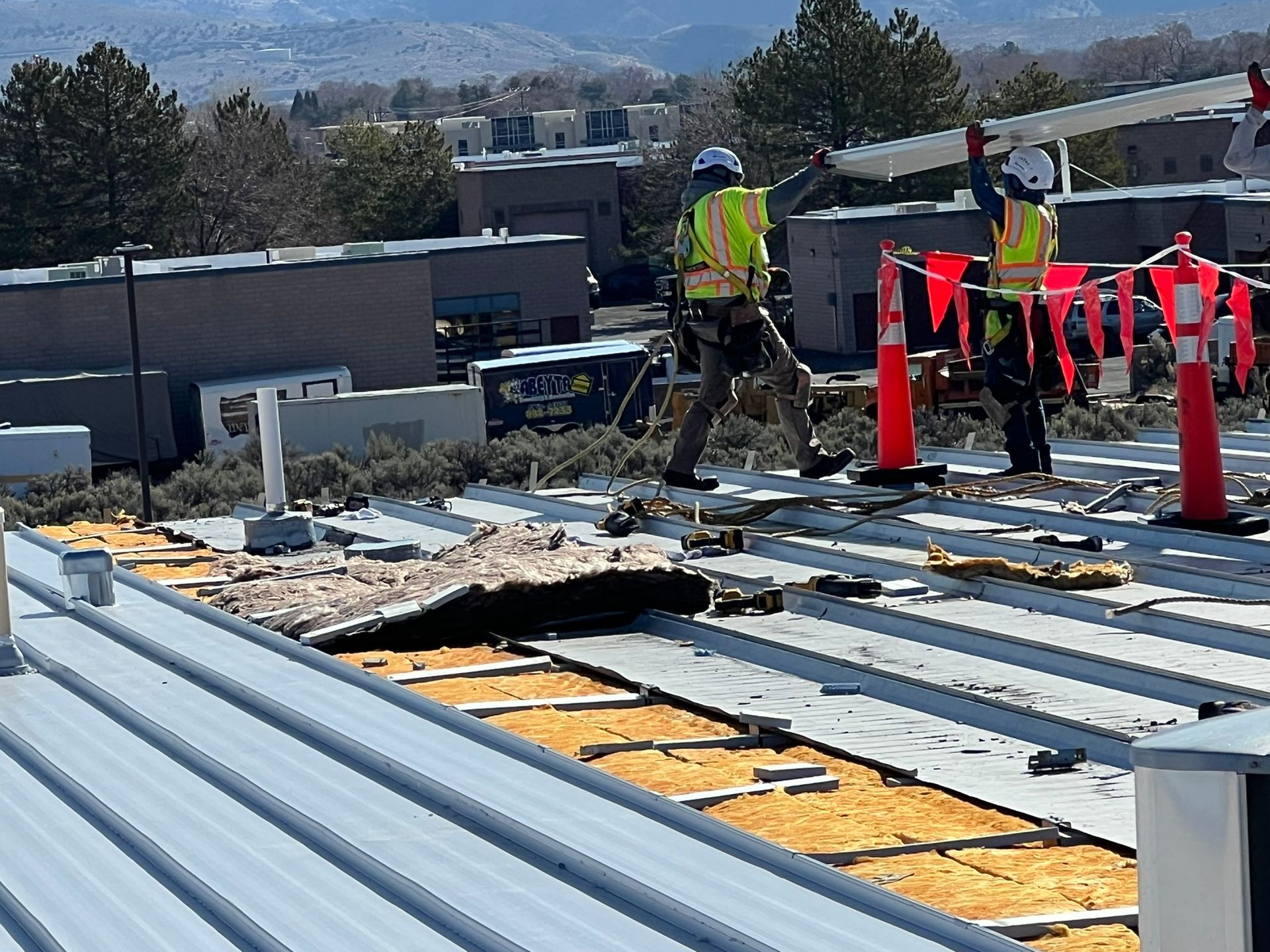 Construction workers installing metal roofing on a building.