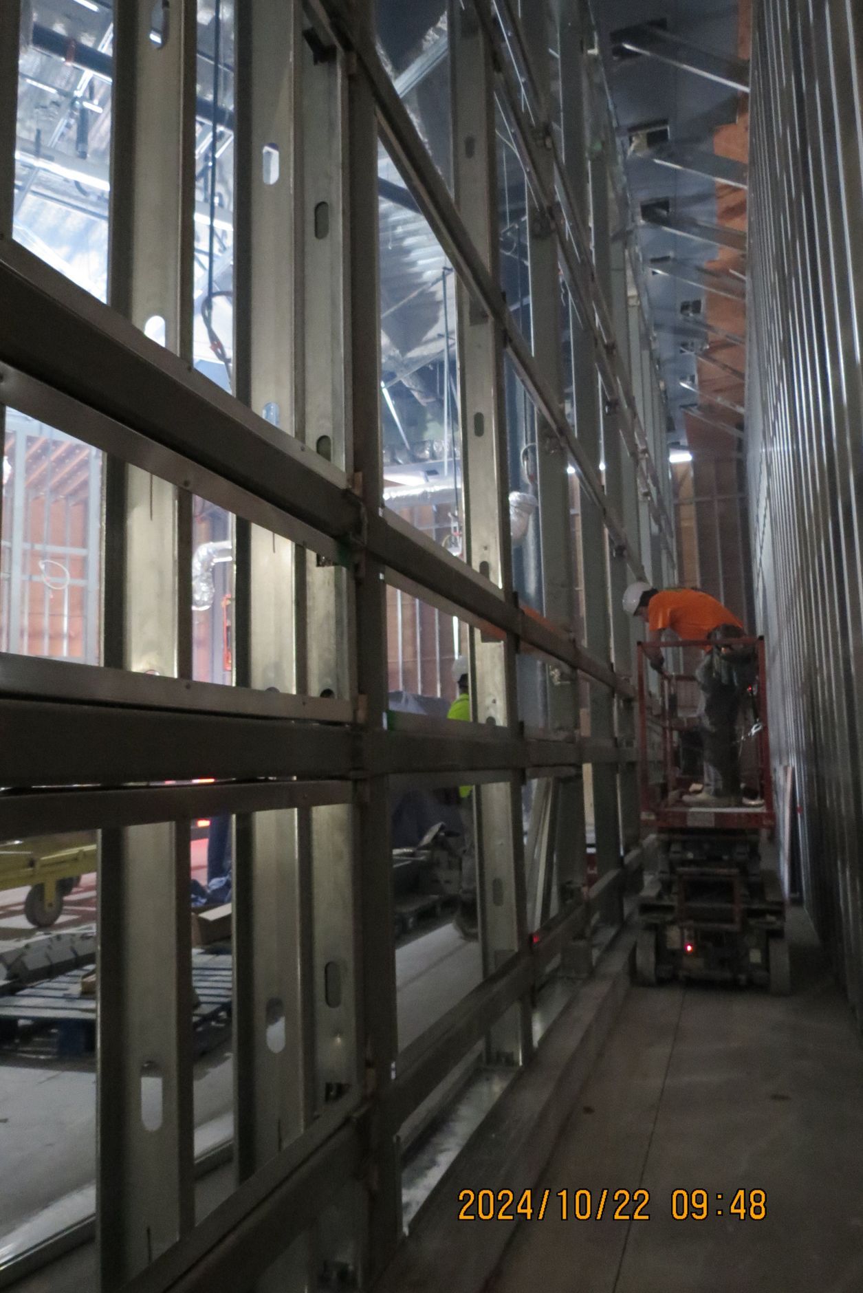 Metal framing of a building under construction; workers on a lift.