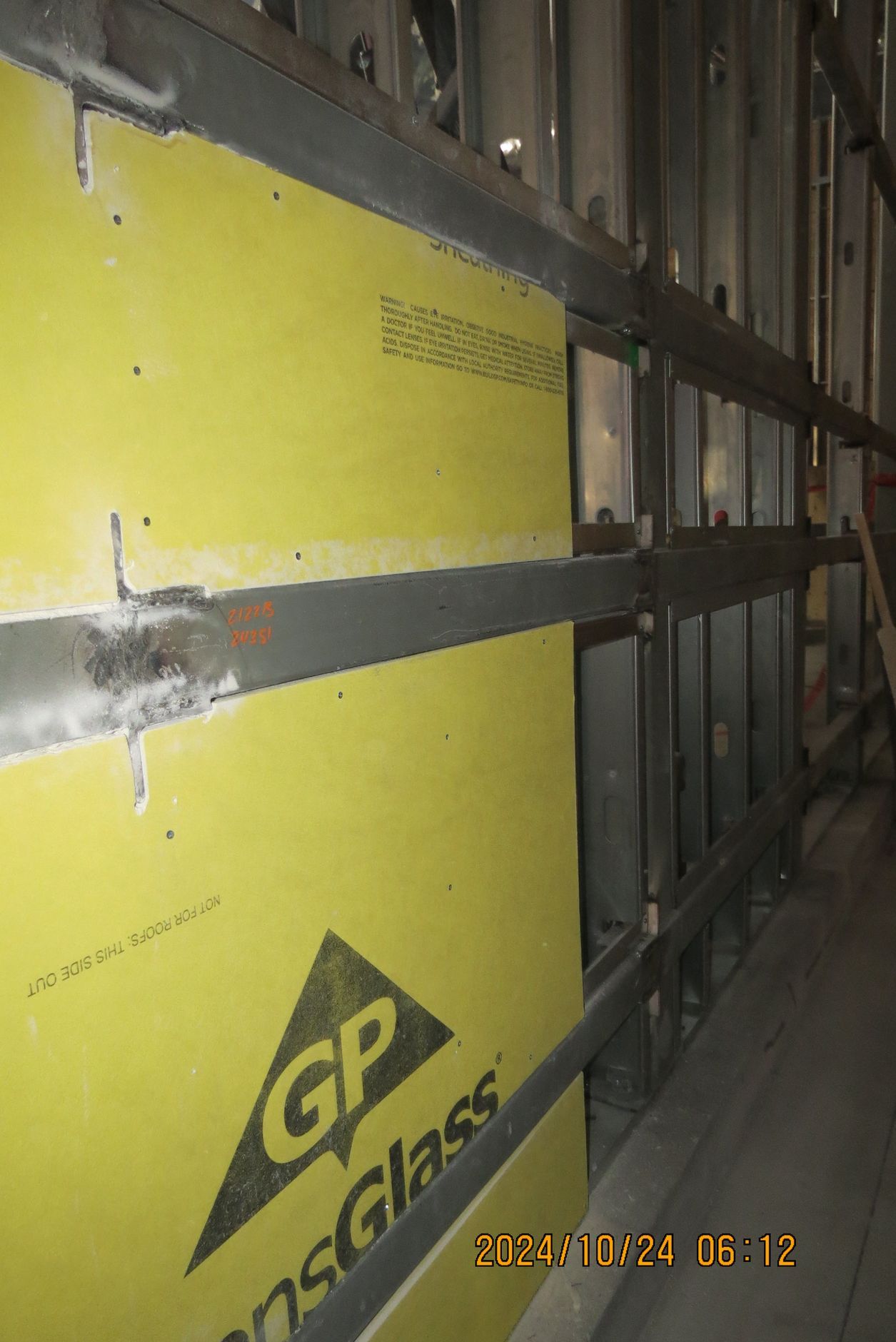 Yellow glass board construction with exposed metal framing in a building.