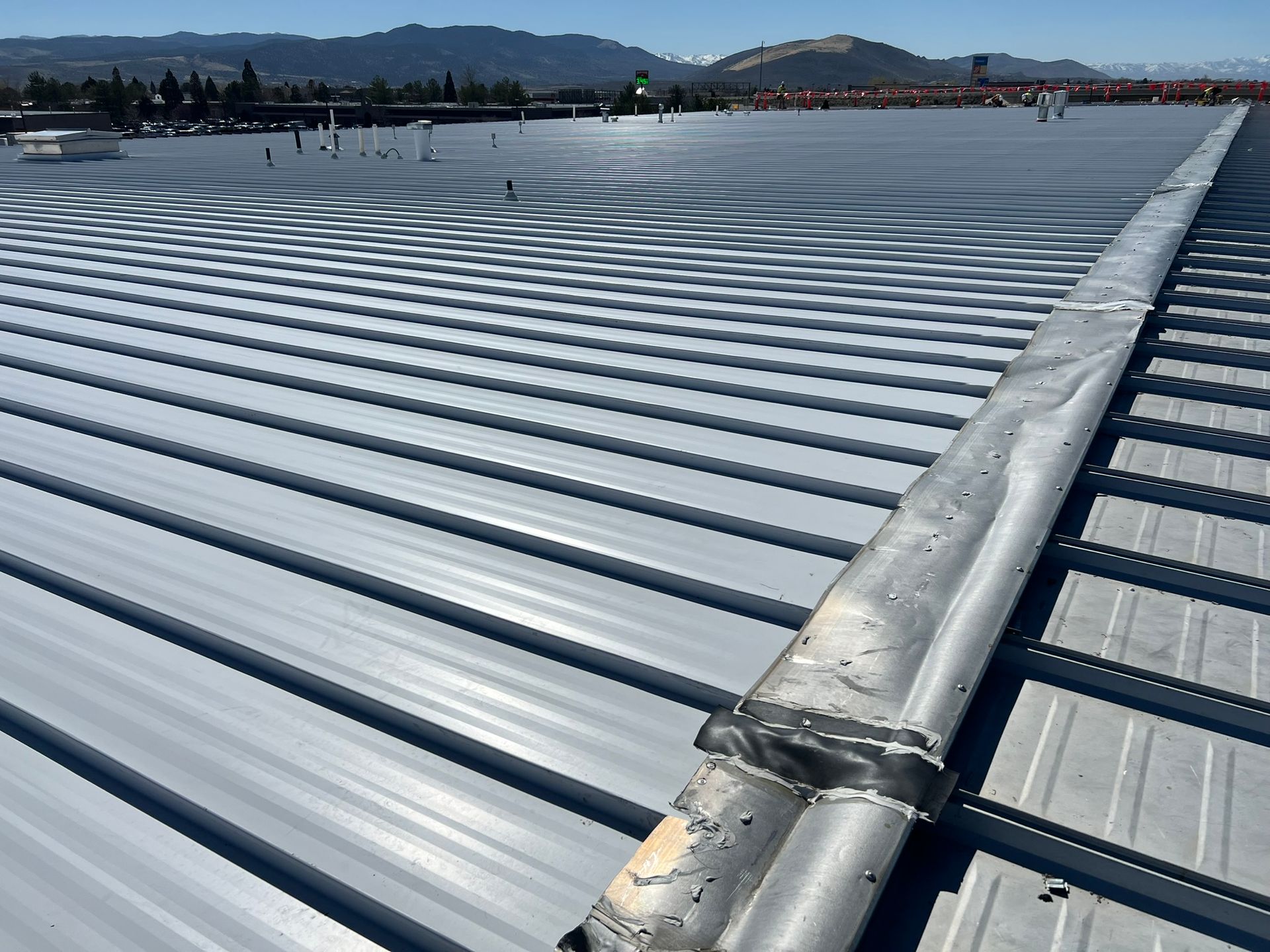 Metal roof with a gutter running along its length on a sunny day.