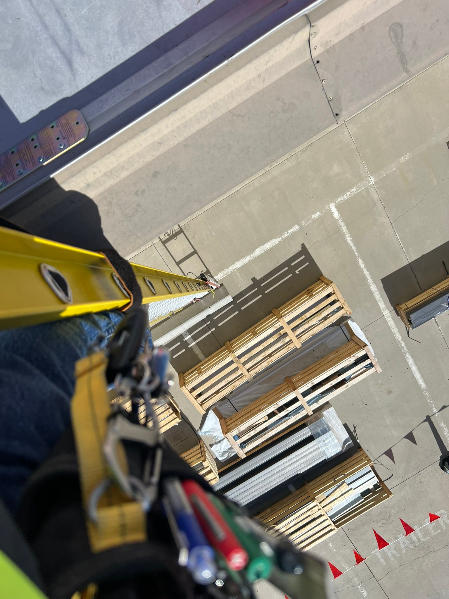 Person using a level on a building project. Work site with lumber stacks and safety cones.