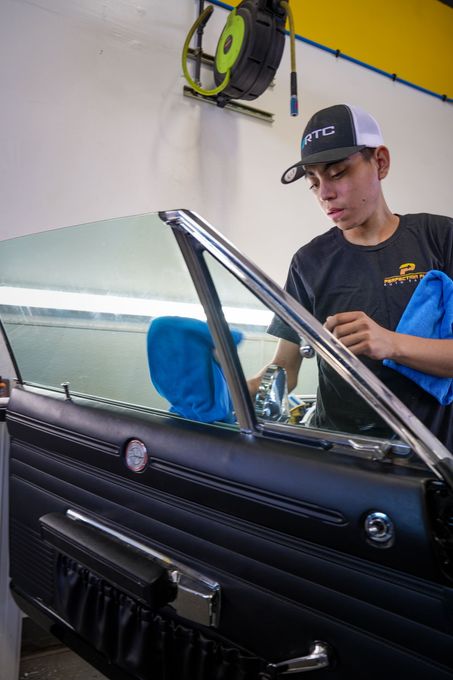 A man is cleaning the window of a car with a towel.