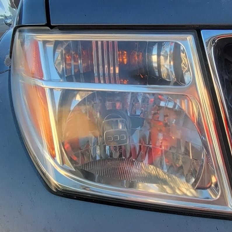 Close-up of a car headlight with a chrome border, showing amber turn signal and clear headlight lens.