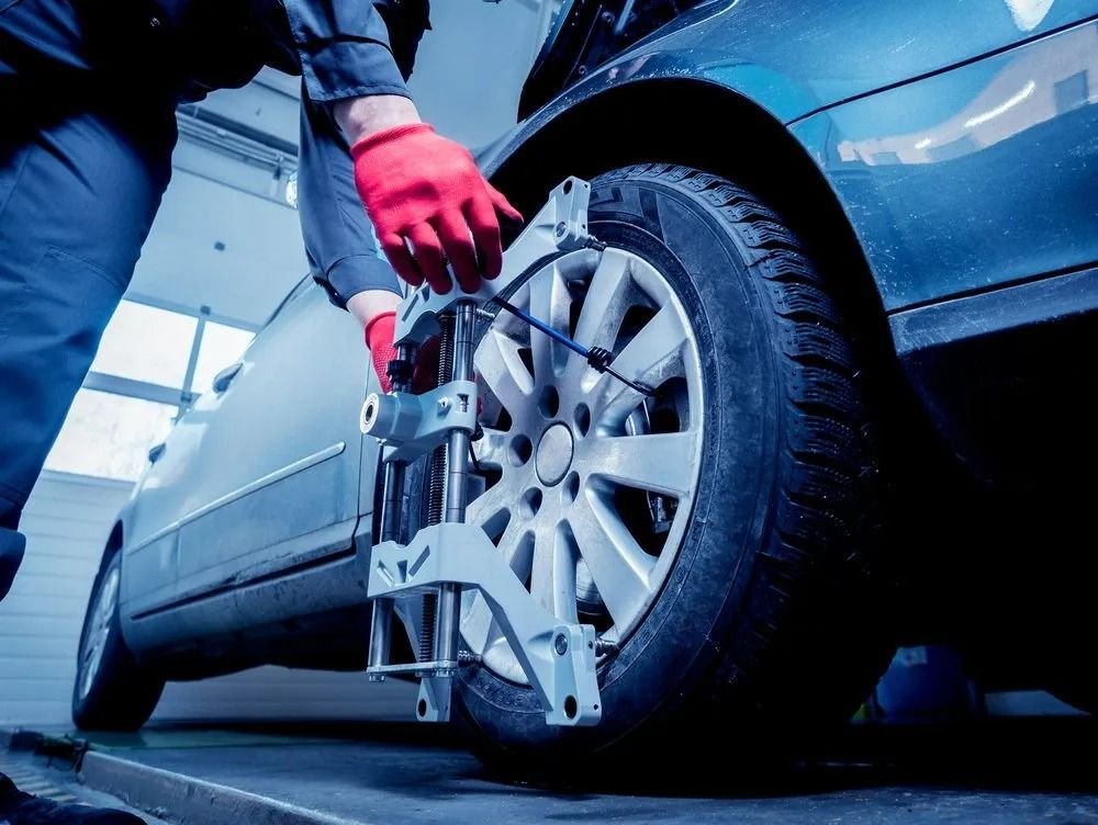 A Technician In Red Gloves Attaches A Wheel Alignment Sensor — THG Tires in Gladstone Central, QLD
