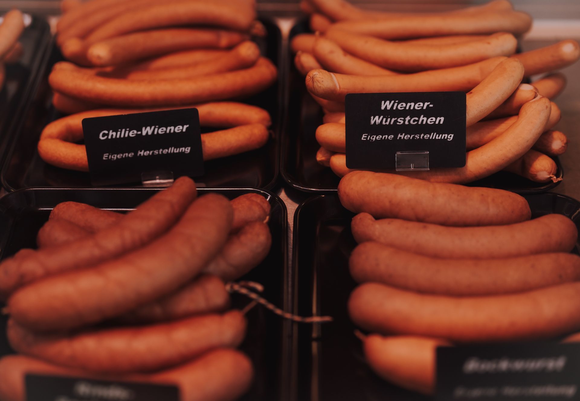 Reihenweise Würstchen in einer Vitrine, „Wiener-Würstchen“. Sie variieren in Farbe und Form.