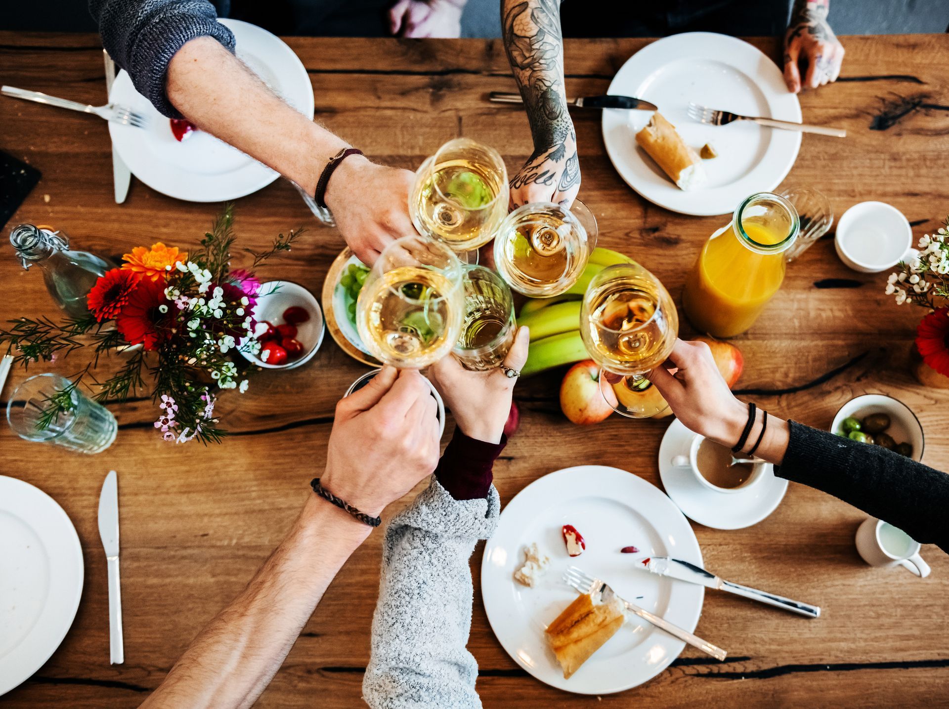 Un gruppo di persone è seduto a un tavolo e brinda con bicchieri di vino.