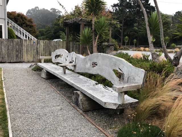 A bench made out of a tree trunk in a garden