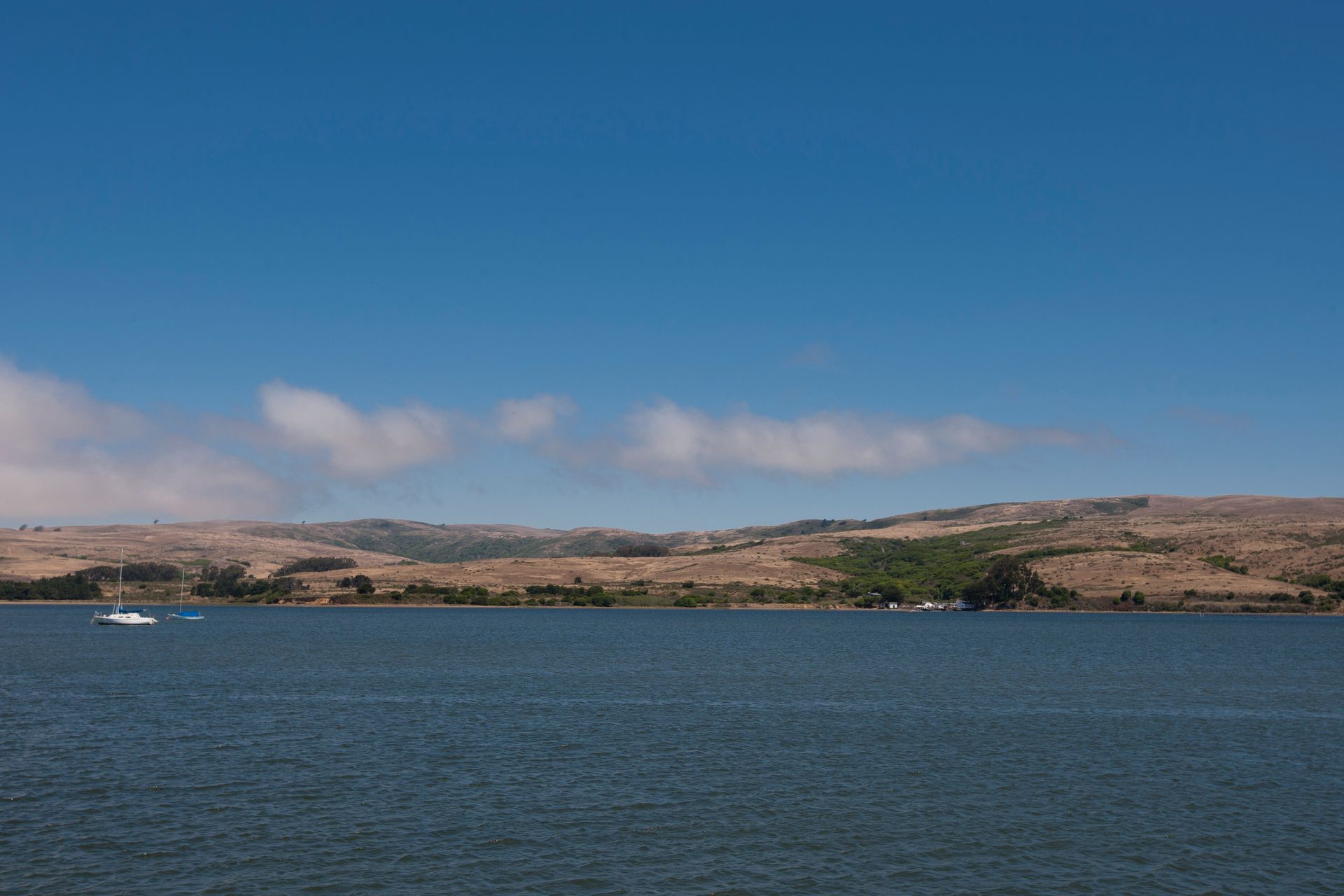A large body of water with mountains in the background and a boat in the water.