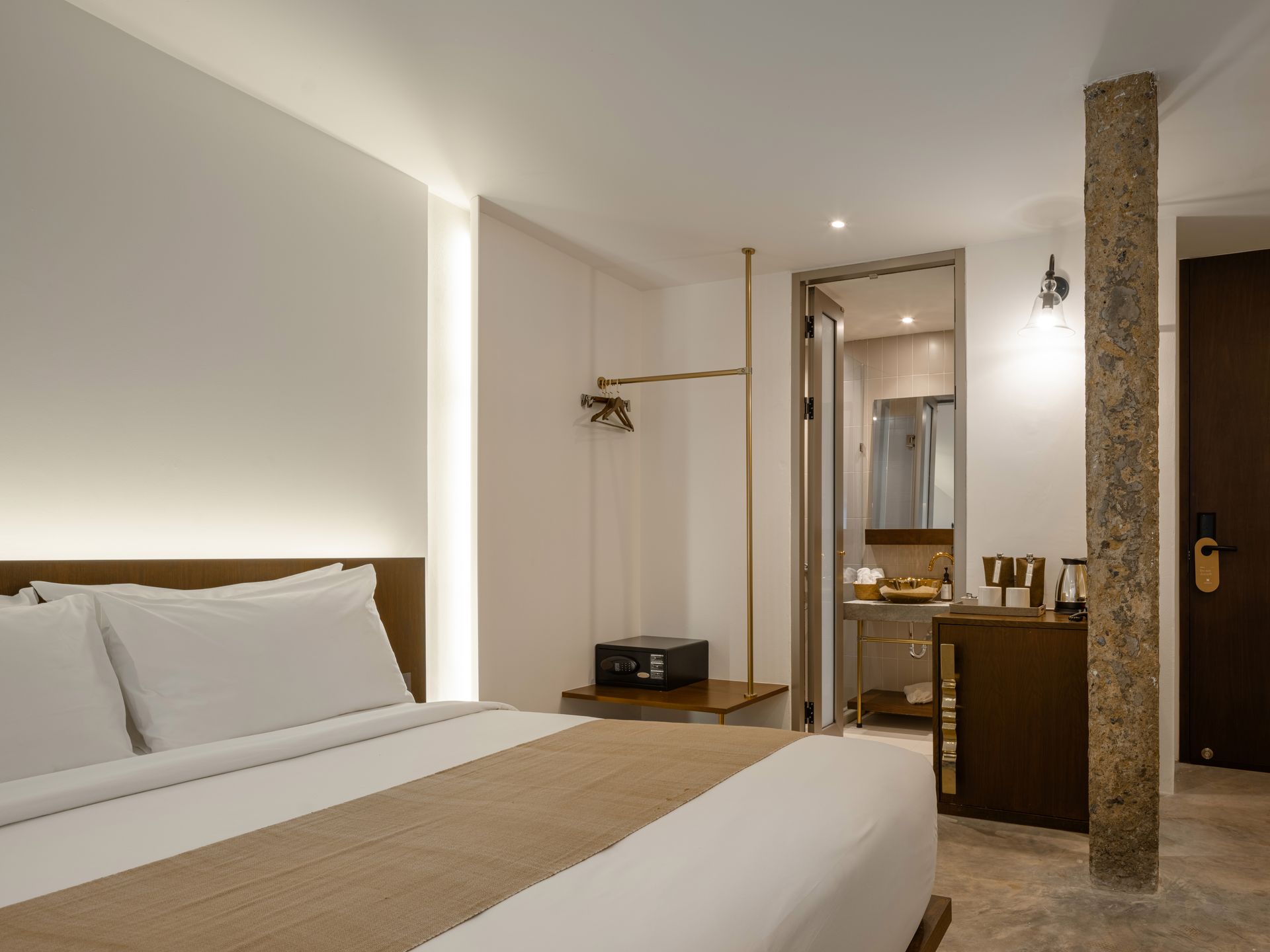Modern bedroom with a large bed, warm lighting, and a small desk by a glass partition
