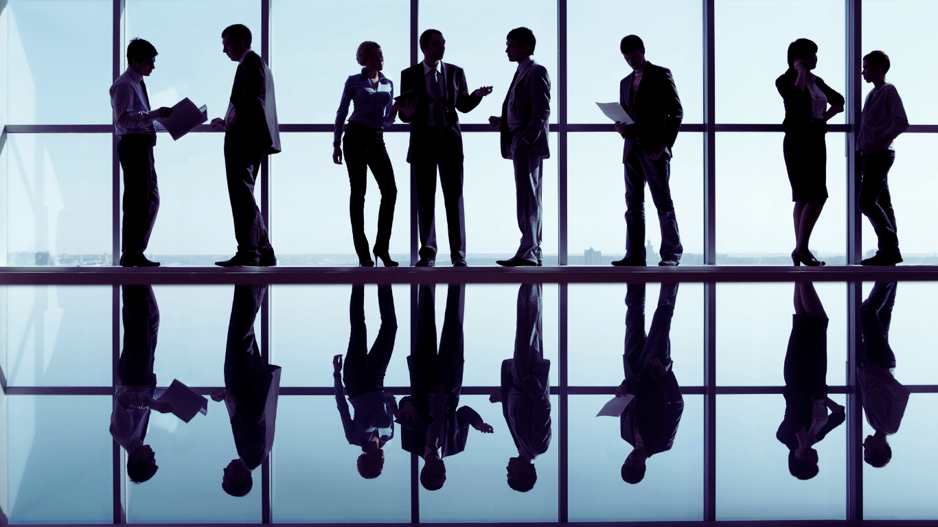 Silhouetted businesspeople standing by windows, some interacting, reflective surface below.