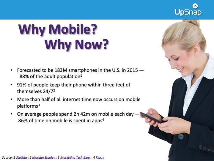 A woman in a suit is smiling while looking at a cell phone with the words why mobile why now on the bottom