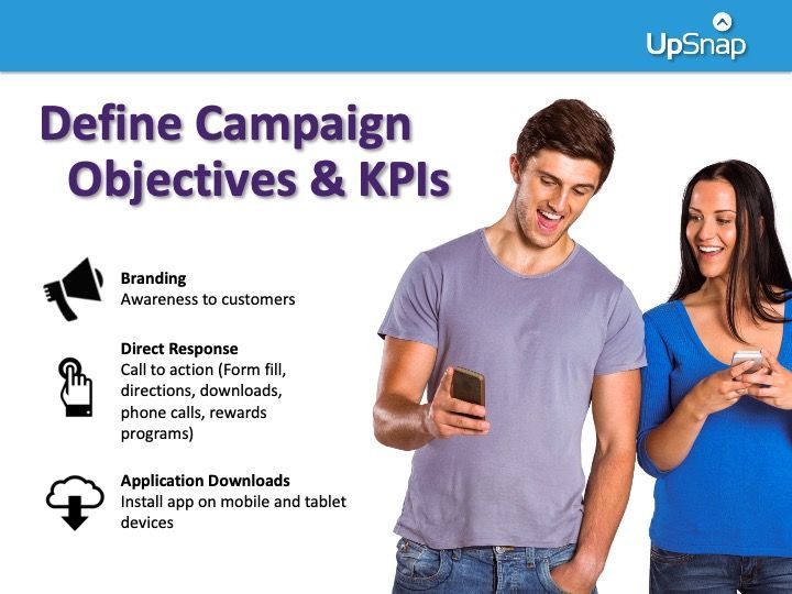 A man and a woman are standing next to each other looking at their phones.