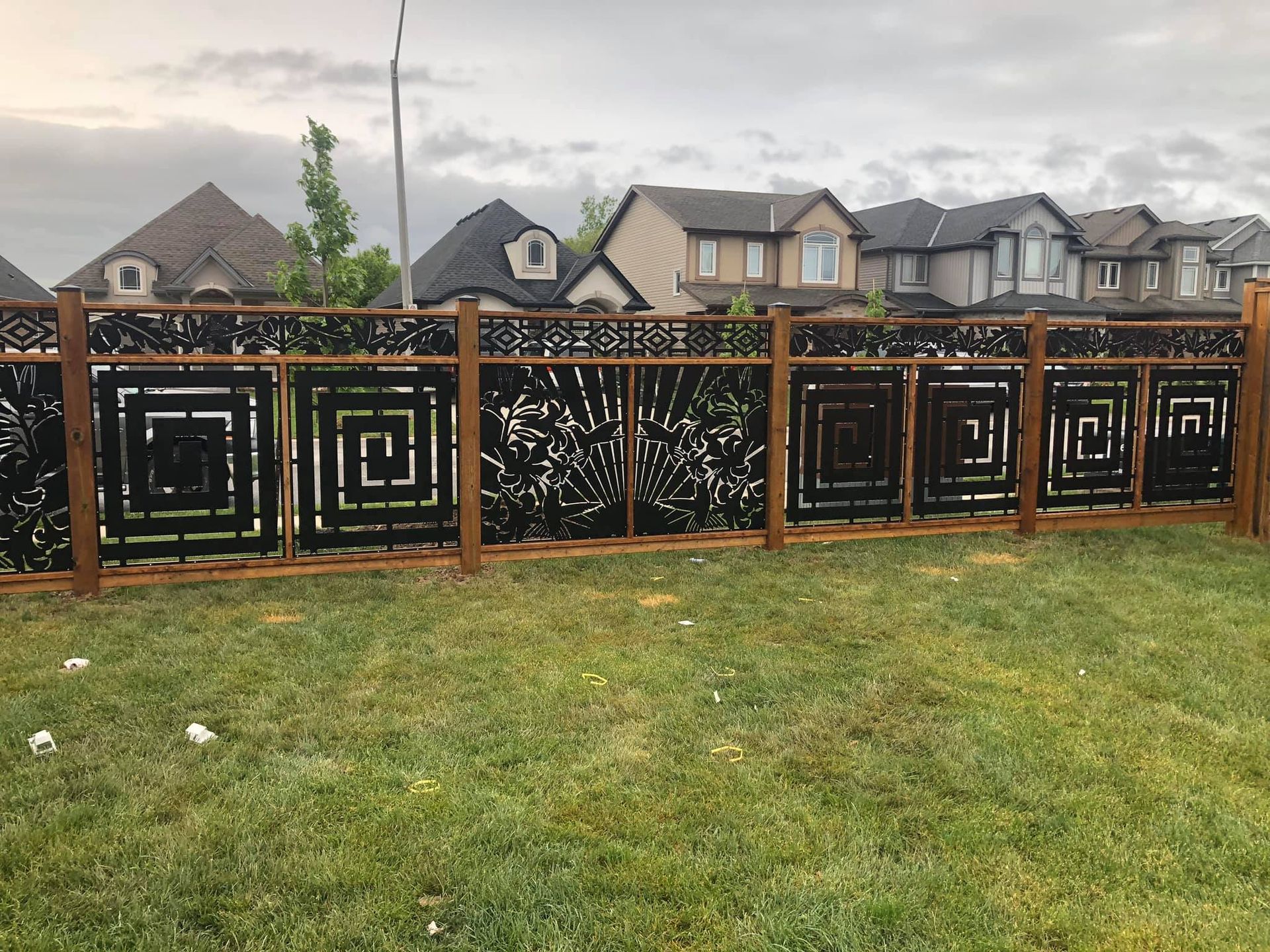 Backyard wooden deck with black gazebo, green lawn, and fenced yard under a blue sky