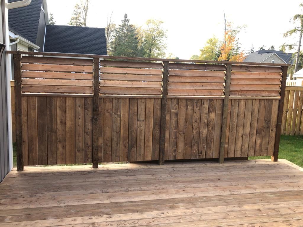Wooden backyard fence with horizontal slats and a paved patio in front