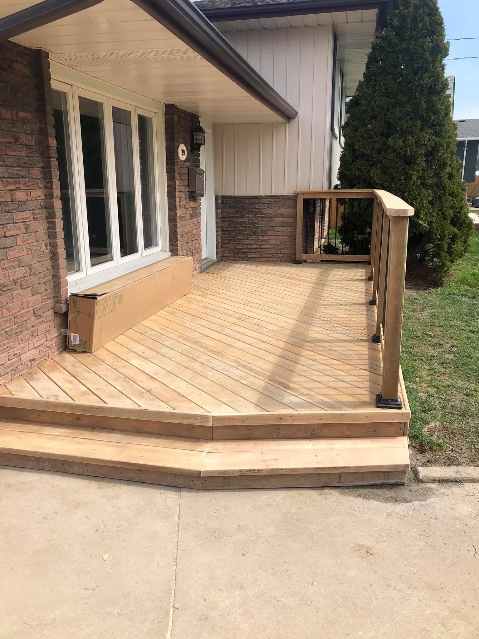 Wooden wheelchair ramp and steps leading to a house entrance, with railing and brick siding.