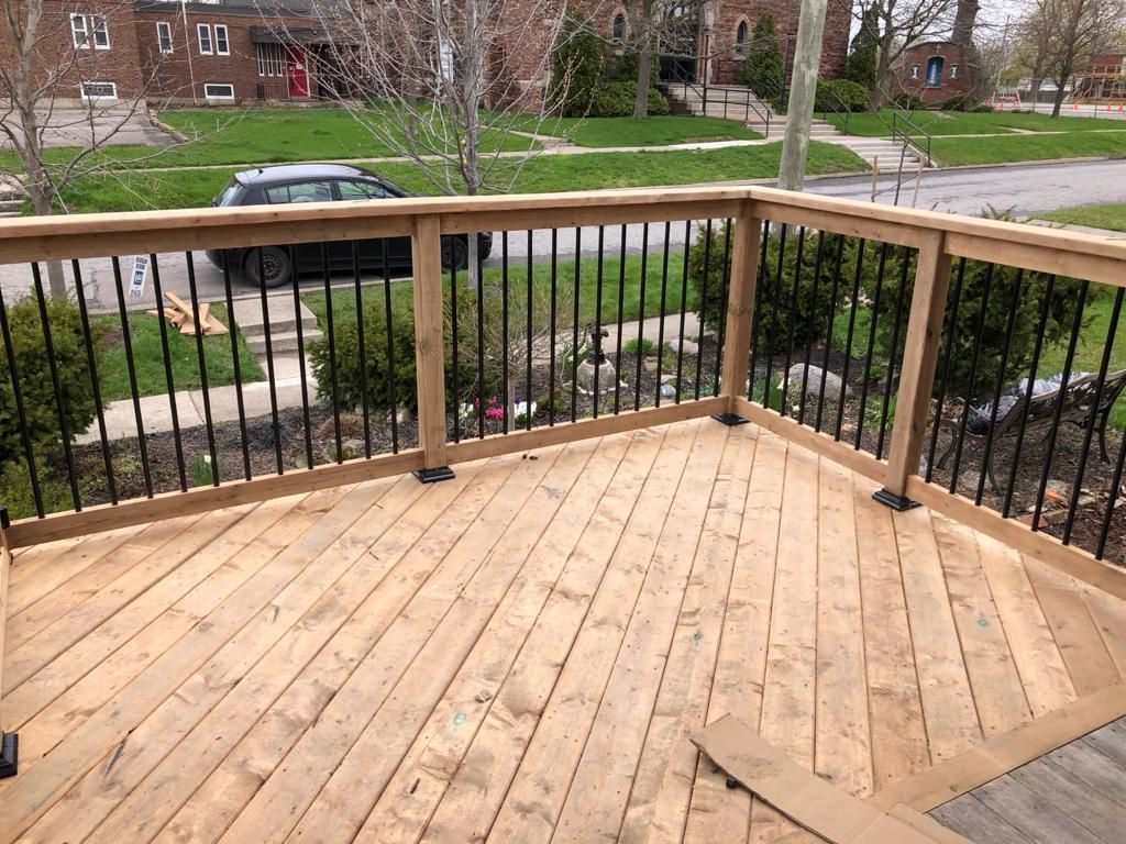 Wooden deck with railing overlooking a residential street and front yard