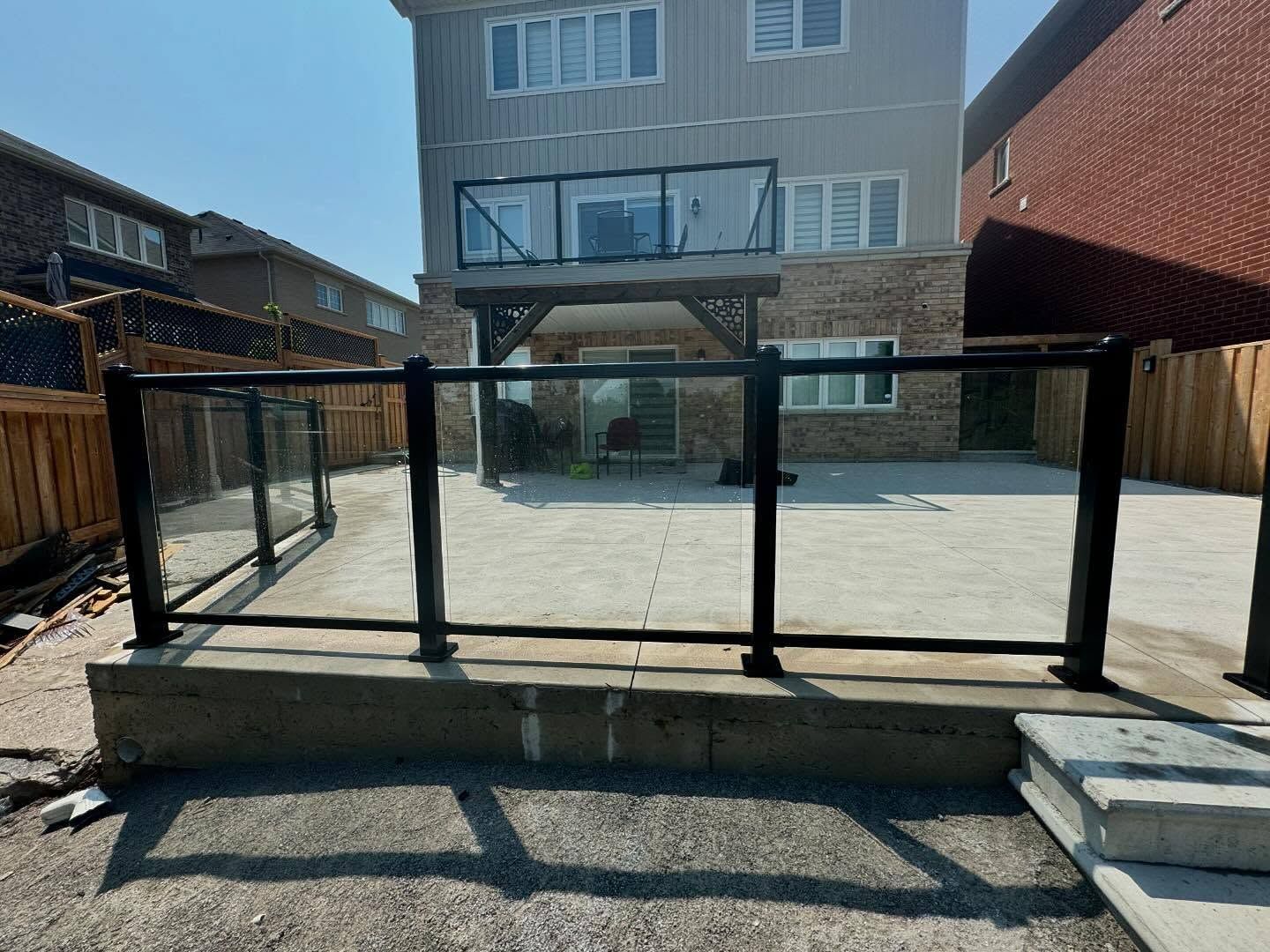 Spacious wooden deck beside a gray house with sliding glass doors and tall trees in the background