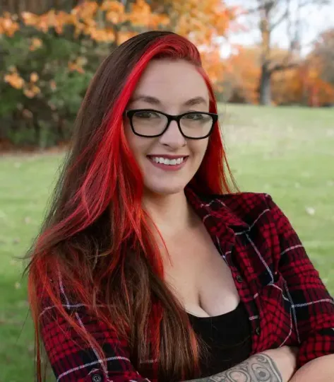 A woman with red hair and glasses is smiling for the camera.