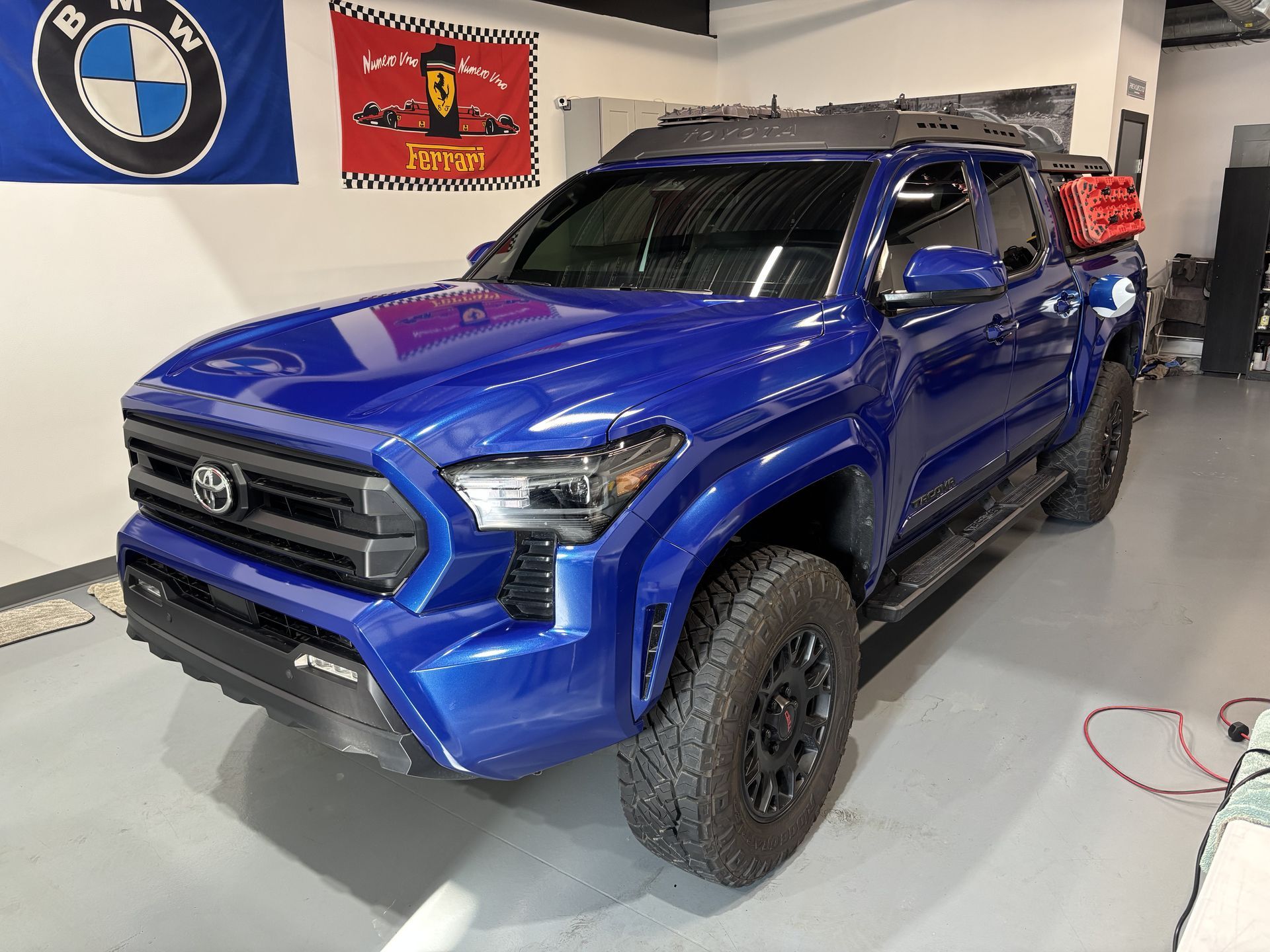 Blue Toyota pickup truck in a garage with BMW and Ferrari wall signs