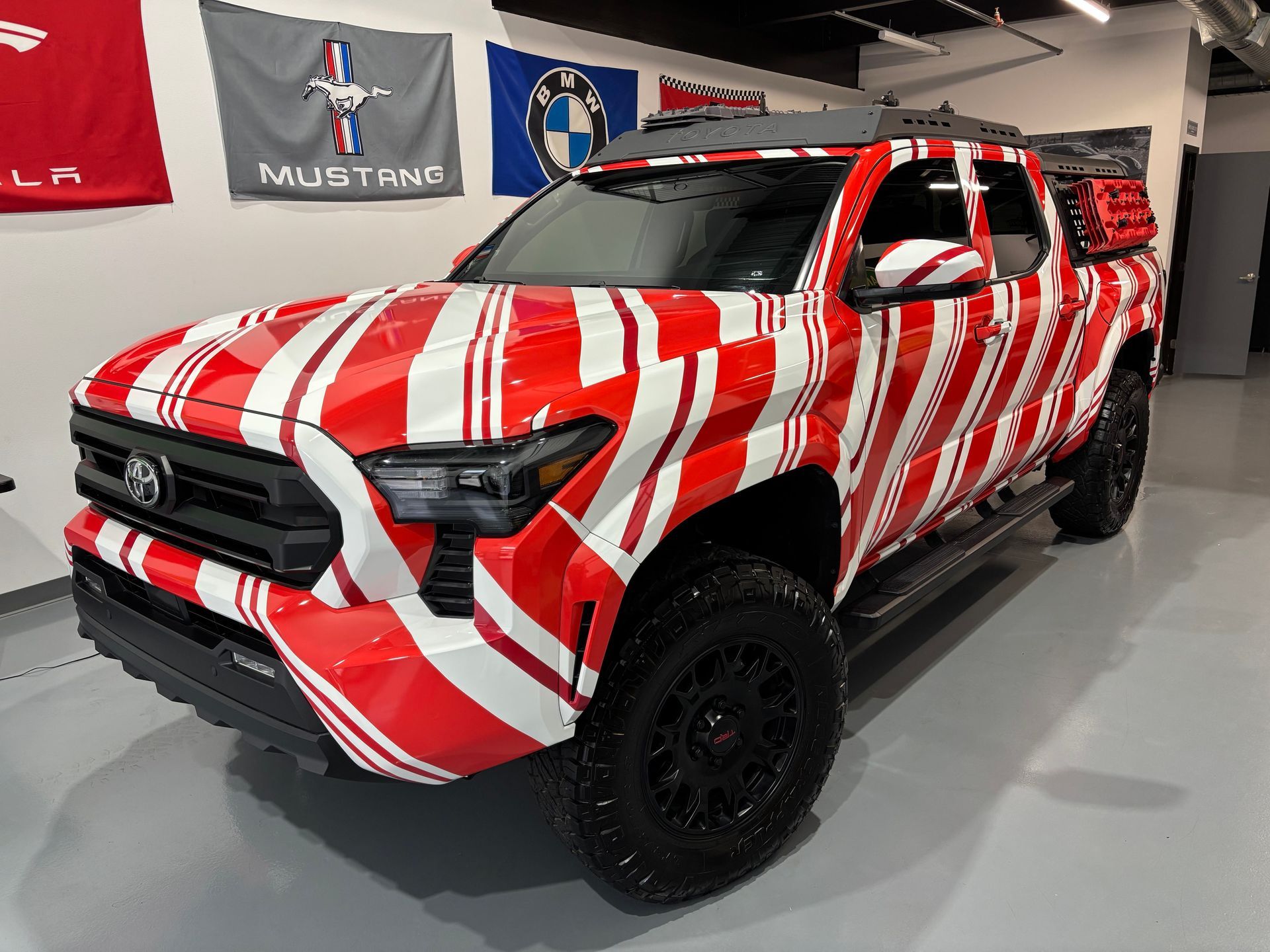 Red-and-white striped custom pickup truck displayed indoors on a showroom floor.