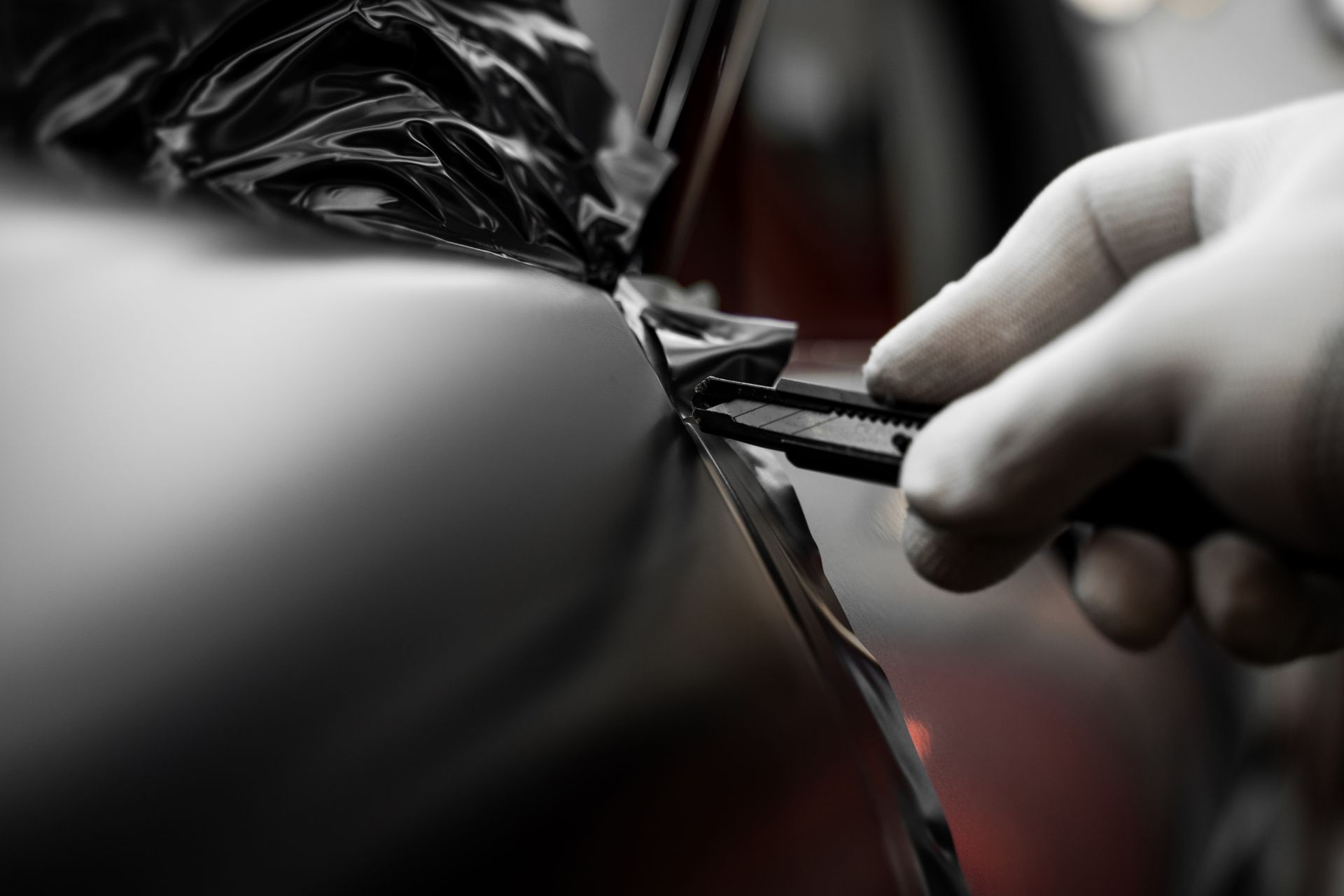 Gloved hands pull a black cable tie tight around a wrapped object in a close-up shot