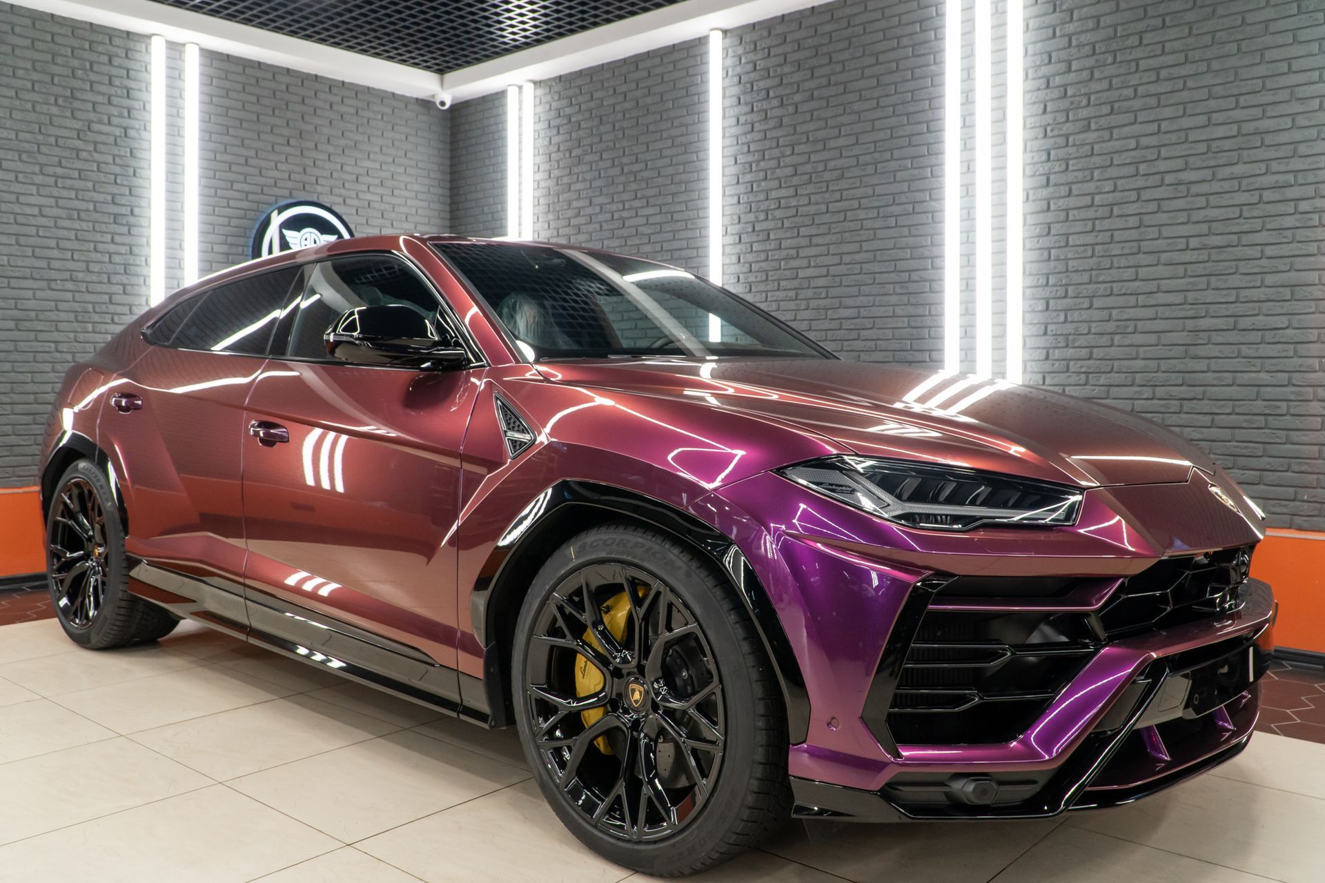 Glossy purple and maroon sports car in a showroom with black wheels and brick walls