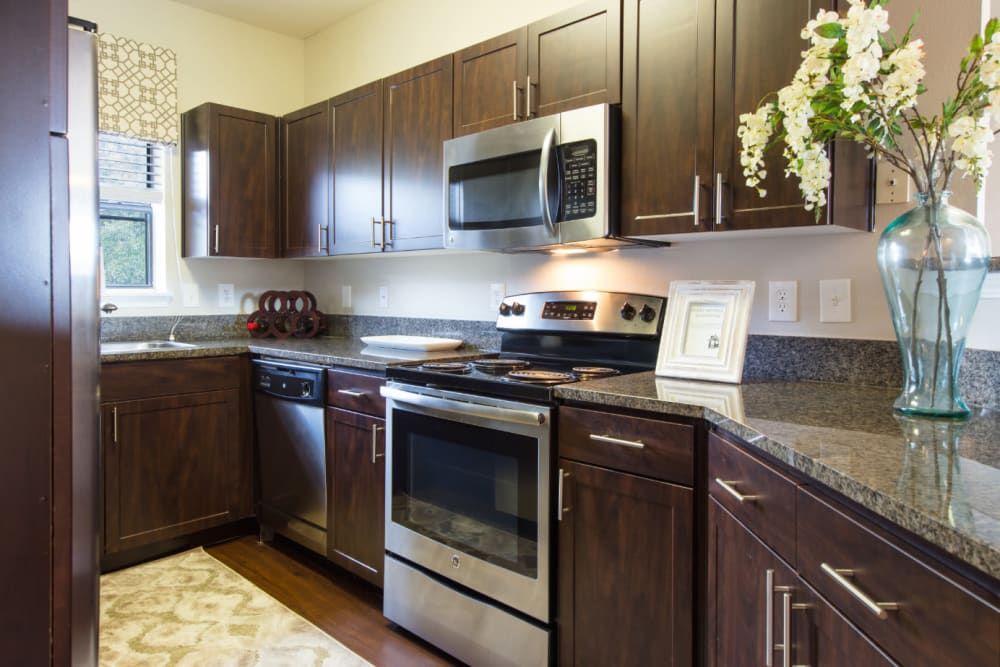 Apartment kitchen with stainless steel appliances and wooden cabinets at Marquis at Treetops in Northwest Austin, TX.