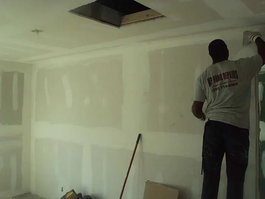 A man is standing in a room with a white wall.