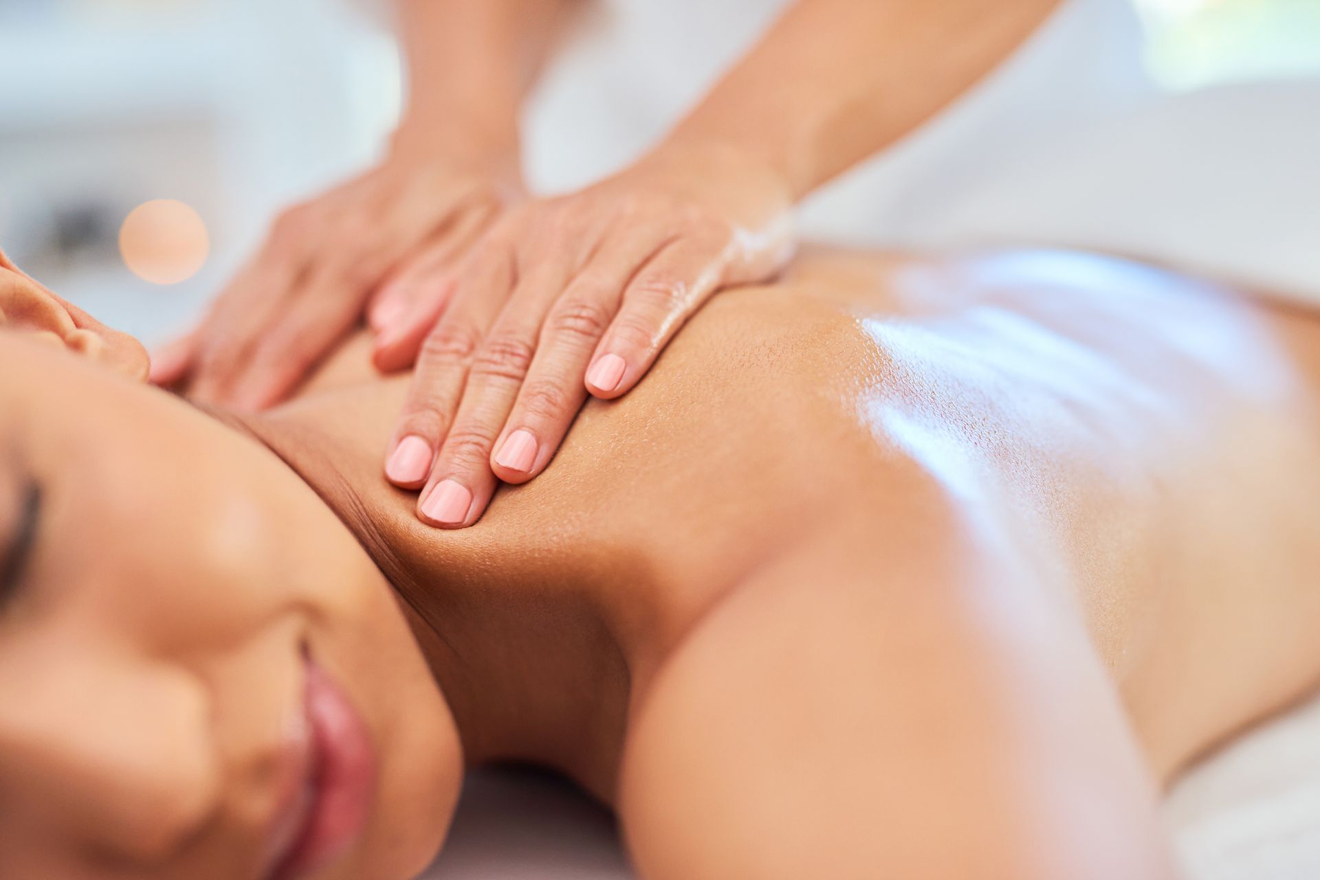 Person receiving a massage on a massage table. Therapist's hands on head and shoulders.