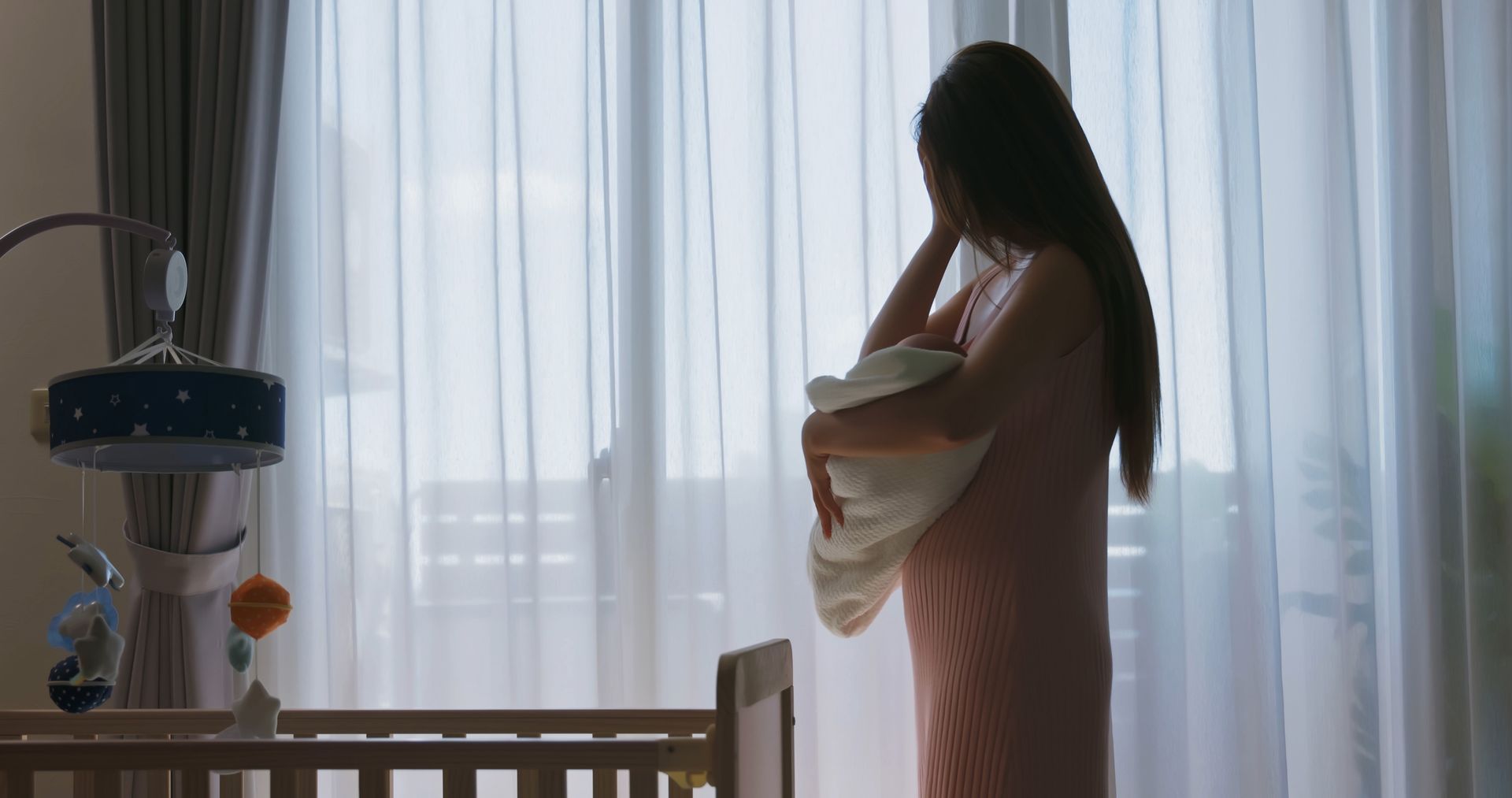 Woman holding baby by window in nursery. Woman holding baby by window in nursery.
