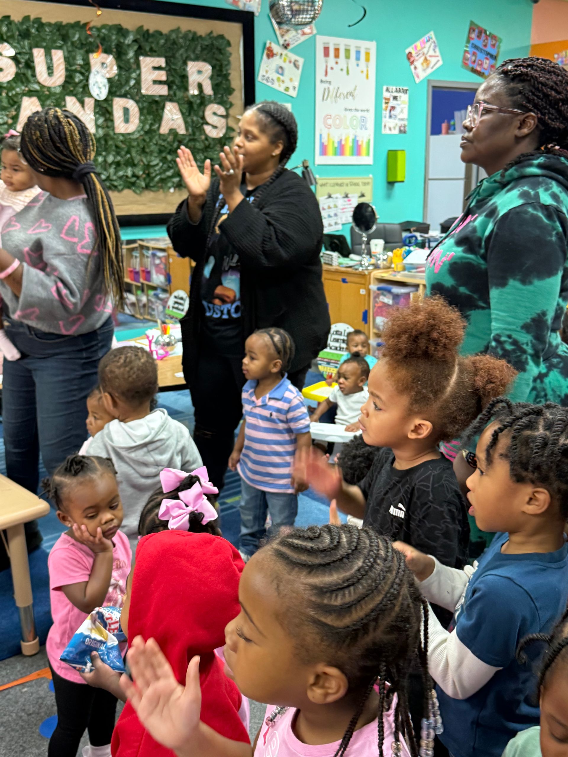 Children and adults clap in a classroom. 