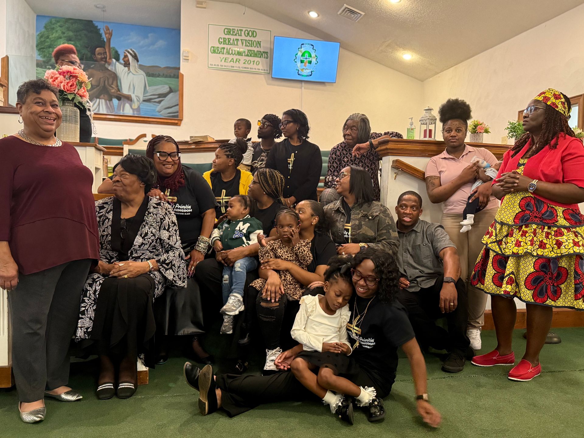 Group of people, mostly in dark clothing, posing indoors at a church. Some are smiling.