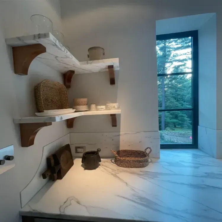 A corner of a kitchen with shelves and a window