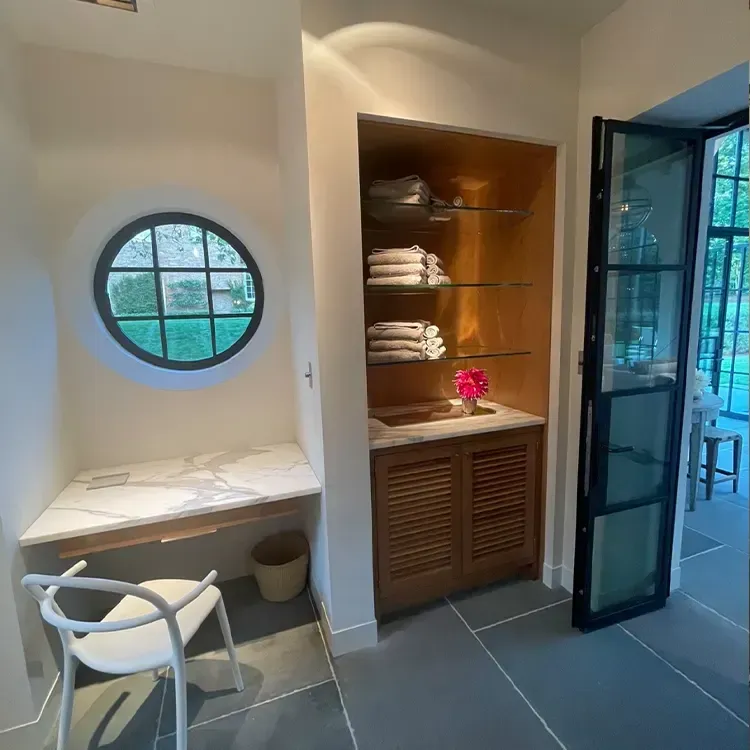 A room with a desk and chair and a round window
