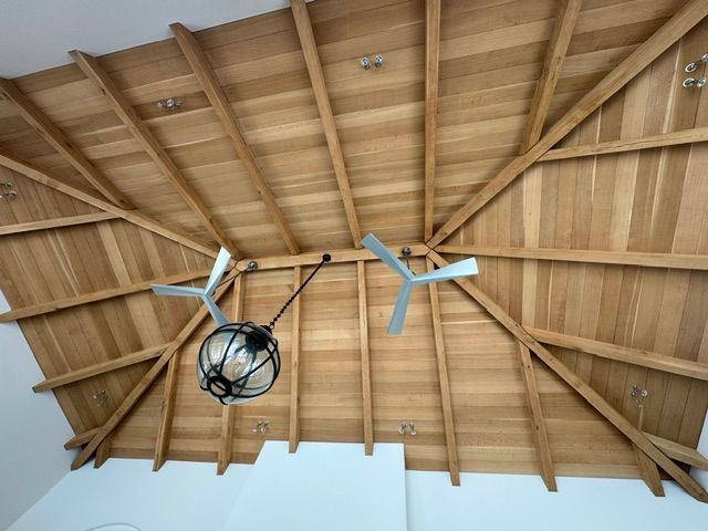 Wooden vaulted ceiling with exposed beams, two ceiling fans, and a hanging light fixture